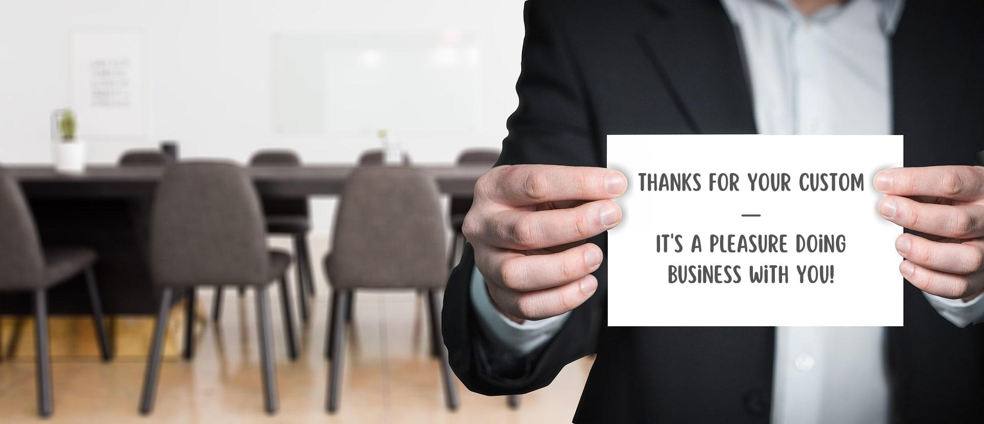 Man in business jacket holding a written card up to the camera, with a boardroom in the background. Image by Gerd Altmann from Pixabay