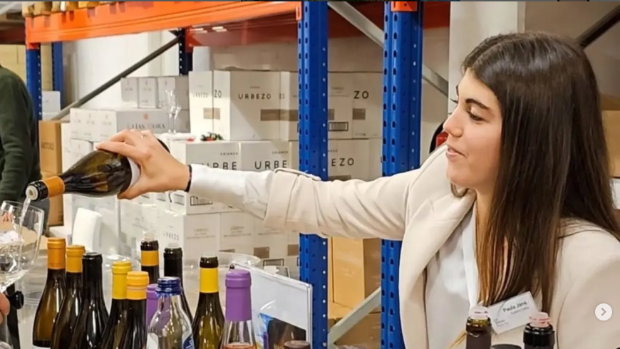 Woman pours wine into a visitor's glass at a trade event.