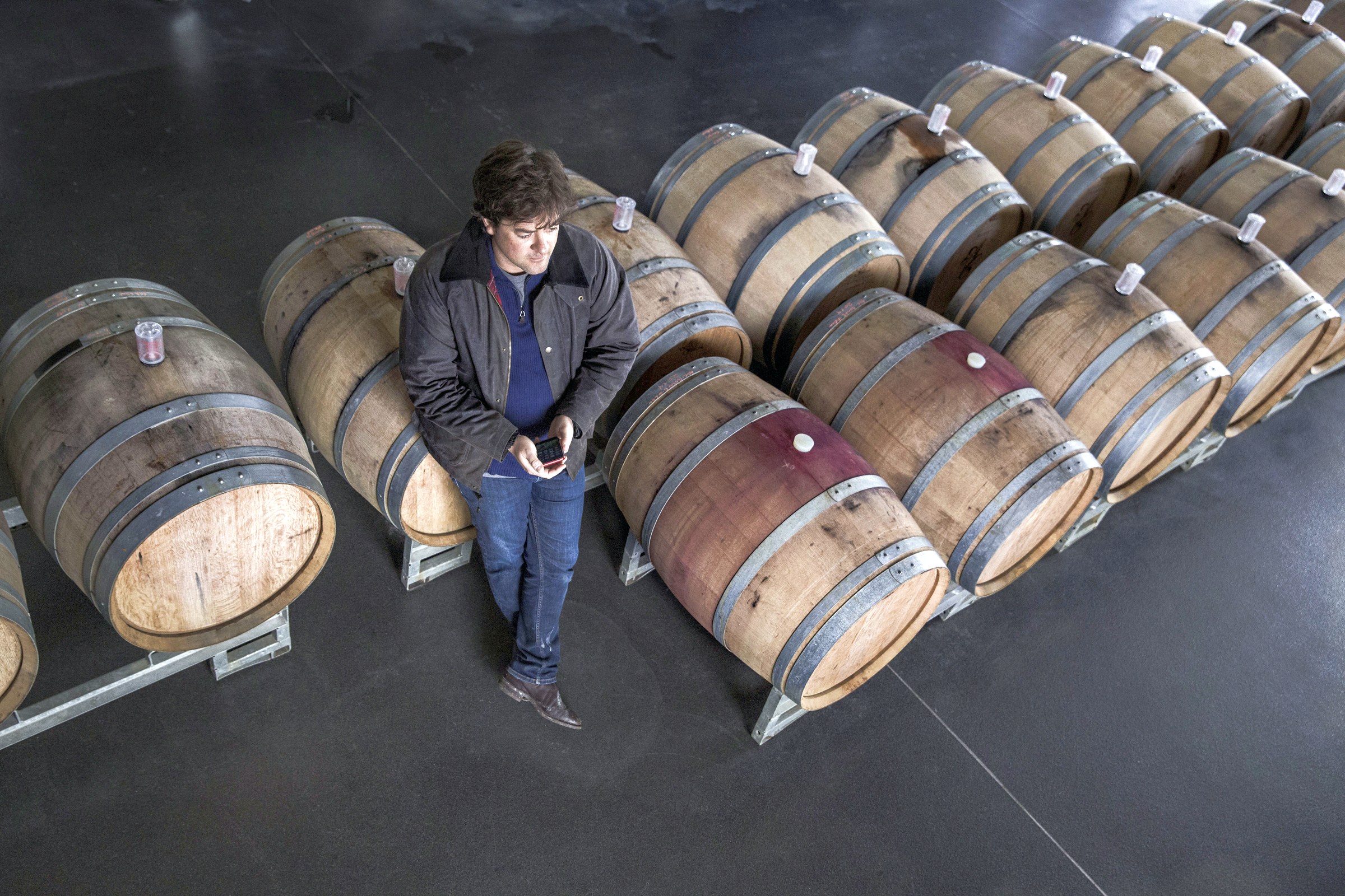Winemaker Jean-François Clouet standing among two rows of barrels in the cellar of his winery.