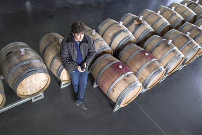 Winemaker Jean-François Clouet standing among two rows of barrels in the cellar of his winery.