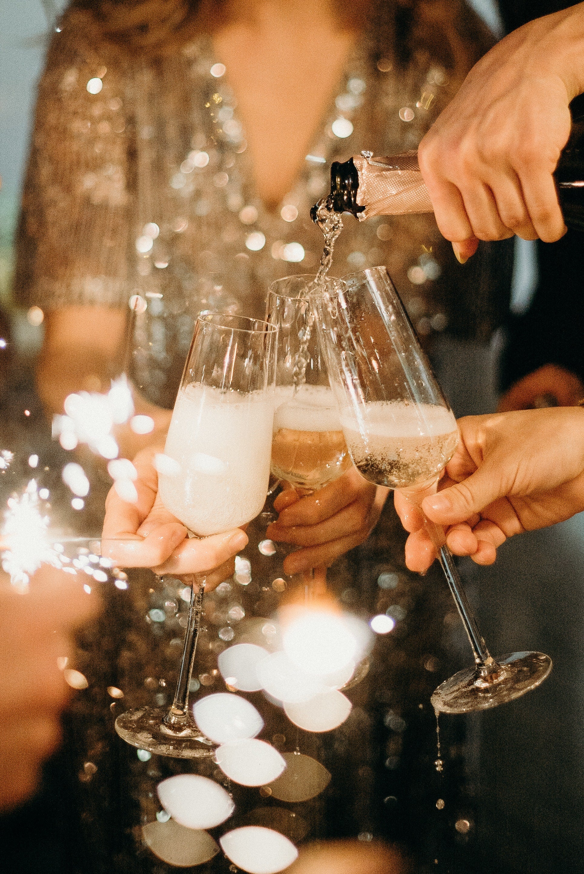 Sparkling wine being served into three glasses
