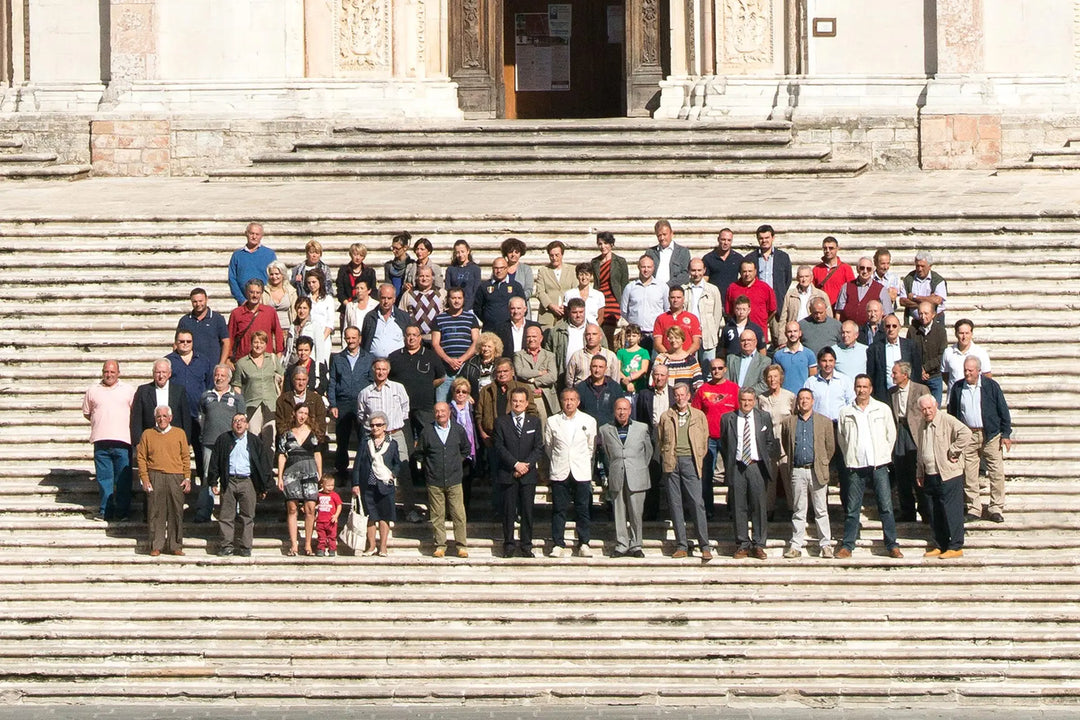 A mixed group of about fifty people standing on the stone steps in front of an old building.