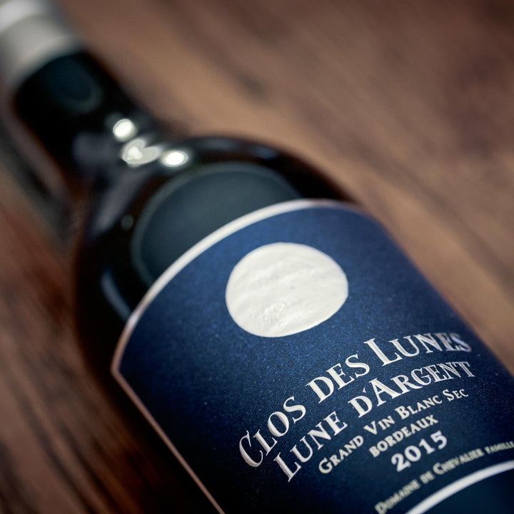 Close-up of a wine bottle labeled 'Clos des Lunes Lune d'Argent' with a wooden background.